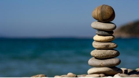 Erikokoiset kivet tasapainossa päällekkäin meren rannalla. Kuvituskuva.